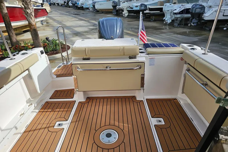 Slide: The Image of 2025 Ranger Tugs R-27 boat interior with teak flooring and seating, docked among other boats. - 12
