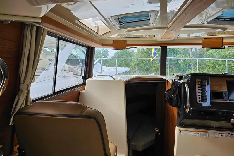 Slide: The Image of Interior view of 2025 Ranger Tugs R-27 boat, featuring helm and seating area. - 14