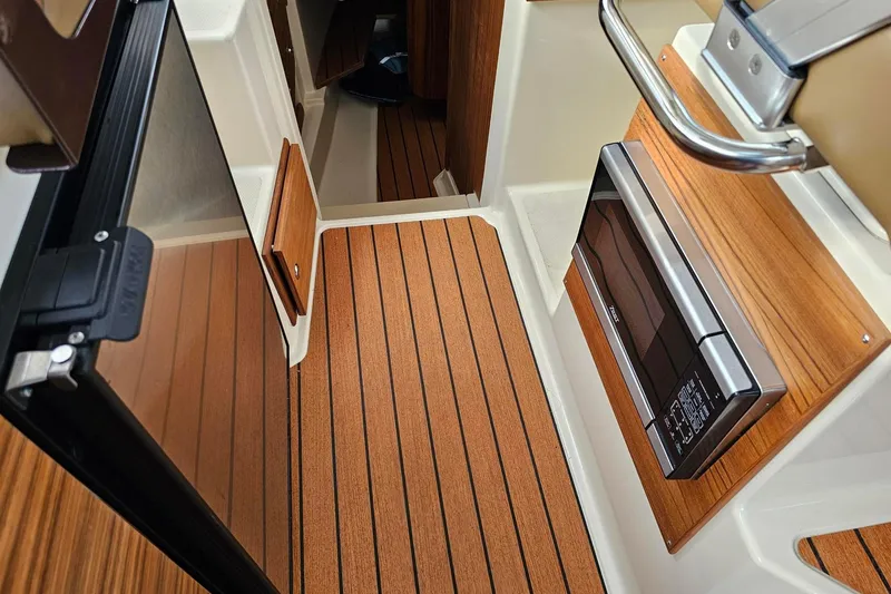 Slide: The Image of 2025 Ranger Tugs R-27 interior with wood flooring and modern appliances. - 16