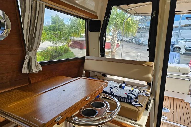 Slide: The Image of Interior of 2025 Ranger Tugs R-27 with wooden table and seating, dockside view. - 17
