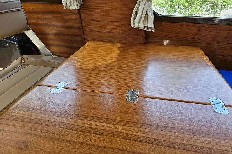 Slide: The Image of Interior of 2025 Ranger Tugs R-27, featuring a wooden table with metal hinges. - 18