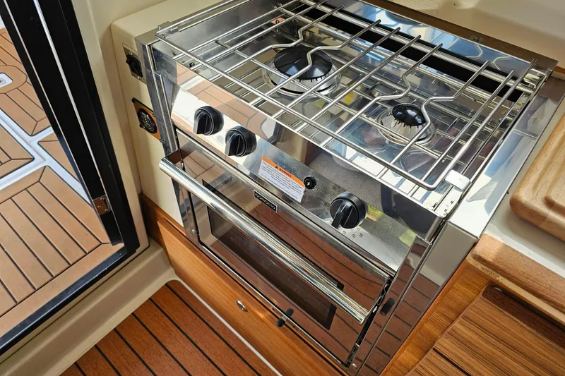Slide: The Image of 2025 Ranger Tugs R-27 boat kitchen with stainless steel stove and oven. - 19
