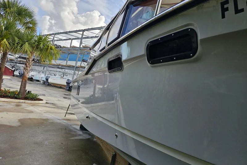 Slide: The Image of 2025 Ranger Tugs R-27 boat docked near palm trees and other vessels. - 6