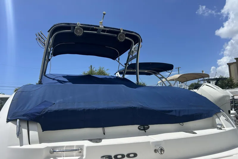 Slide: The Image of 2011 Sea Ray 300 Sundeck boat with blue cover, docked under clear sky. - 26