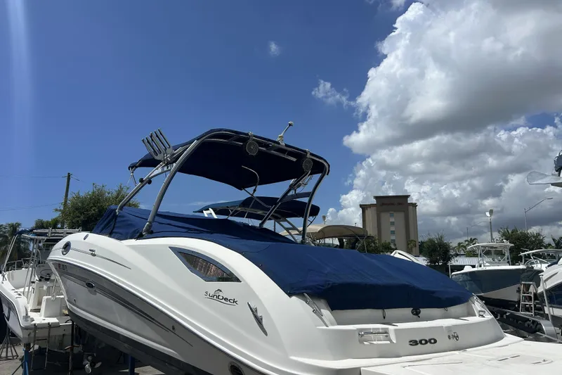 Slide: The Image of 2011 Sea Ray 300 Sundeck boat with blue cover under a cloudy sky. - 28
