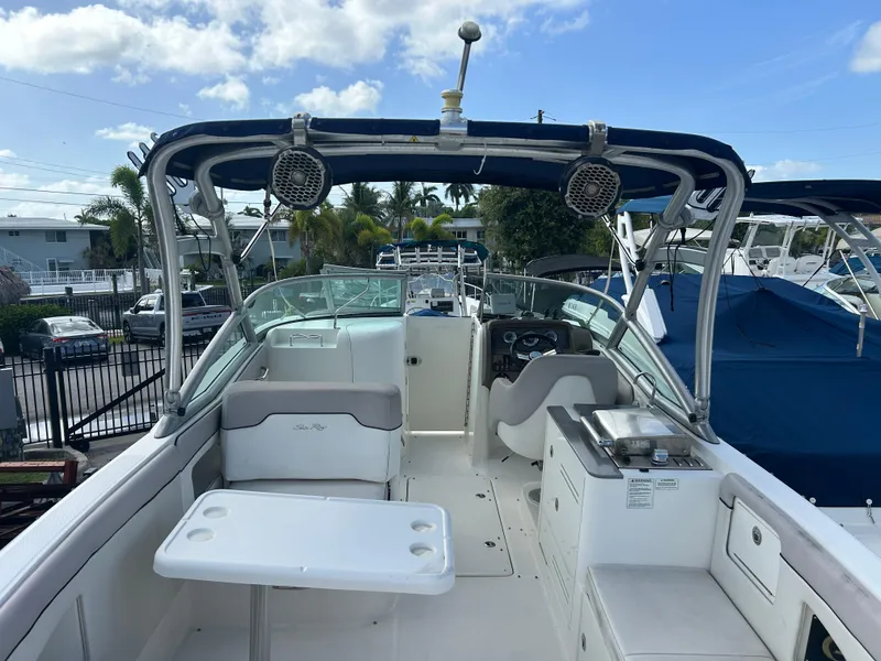 Slide: The Image of 2011 Sea Ray 300 Sundeck boat interior with seating, table, and helm under blue sky. - 4