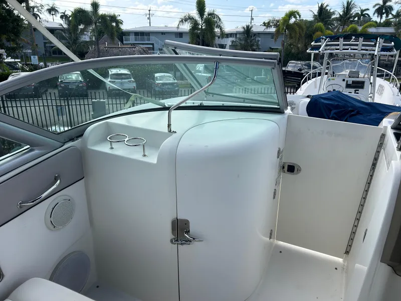 Slide: The Image of 2011 Sea Ray 300 Sundeck interior with windshield, cup holders, and tropical background. - 9
