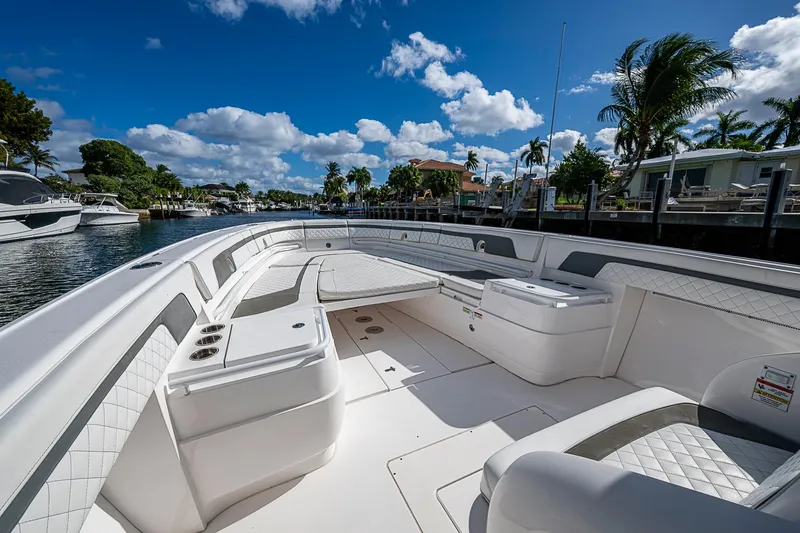 Slide: The Image of 2019 Intrepid 407 Nomad FE boat interior with luxurious seating, docked under a clear blue sky. - 3