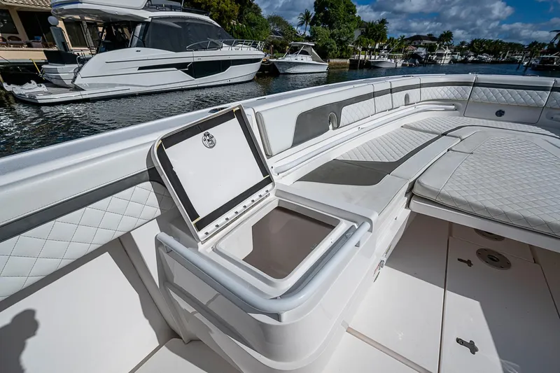 Slide: The Image of 2019 Intrepid 407 Nomad FE boat interior with open storage compartment, docked near other boats. - 4