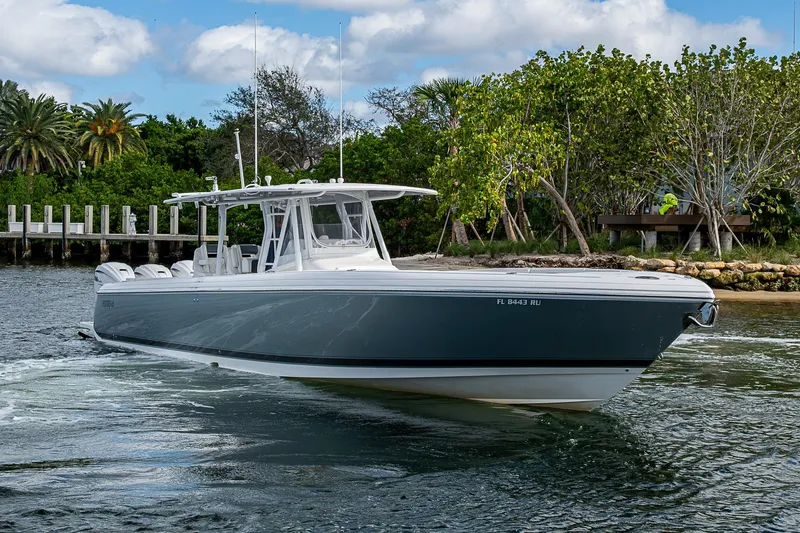 Slide: The Image of 2019 Intrepid 407 Nomad FE boat cruising near lush shoreline. - 40