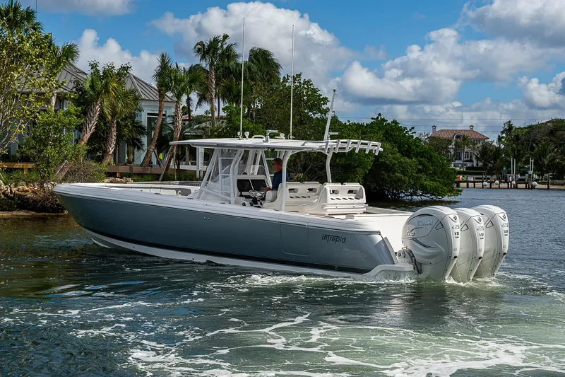Slide: The Image of 2019 Intrepid 407 Nomad FE boat cruising on a sunny day near lush greenery. - 56