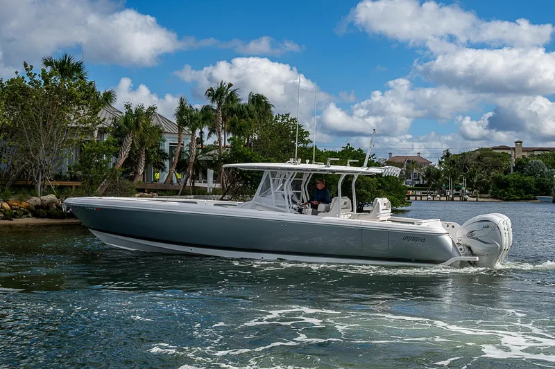 Slide: The Image of 2019 Intrepid 407 Nomad FE boat cruising on a sunny day with palm trees in the background. - 57
