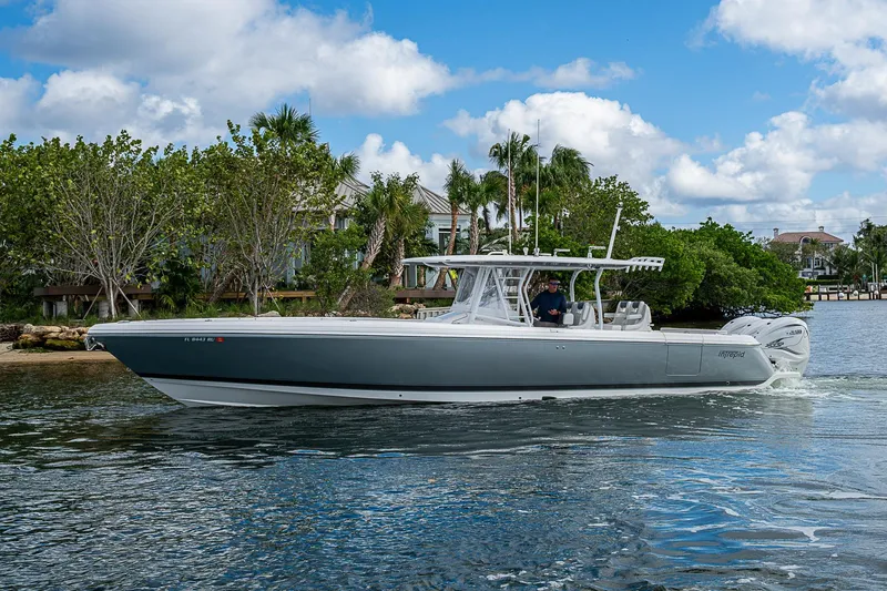 Slide: The Image of 2019 Intrepid 407 Nomad FE boat cruising on a sunny day near lush shoreline. - 59
