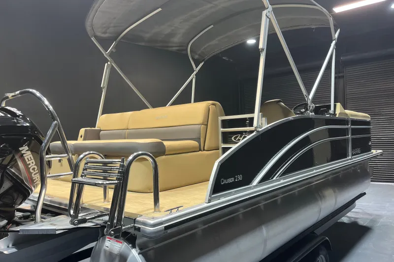 Slide: The Image of 2022 Harris Cruiser 230 pontoon boat with tan seating and Mercury outboard motor. - 4