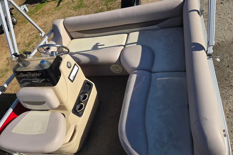 Slide: The Image of 2014 Sun Tracker Bass Buggy 16 DLX pontoon boat interior with beige seating and steering console. - 9