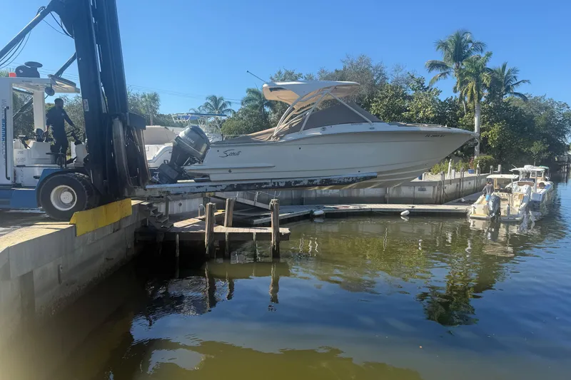 Slide: The Image of 2019 Scout 255 Dorado boat being lifted by a forklift near a dock. - 18