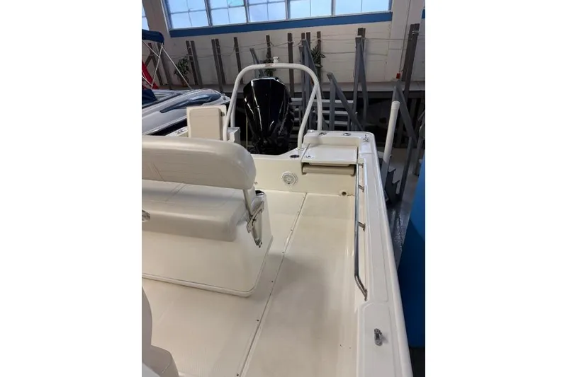 Slide: The Image of 2024 Boston Whaler 210 Montauk boat interior with seating and motor in showroom. - 12