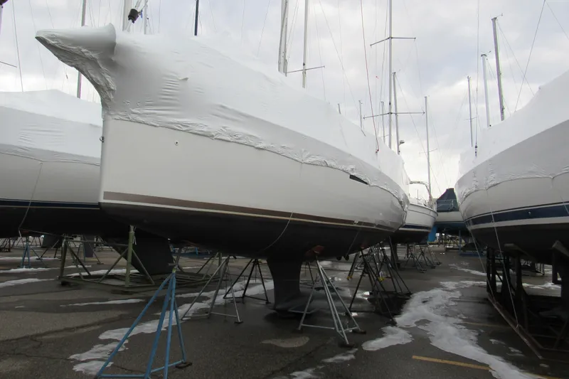 Slide: The Image of 2023 Jeanneau Sun Odyssey 349 sailboats in winter storage, covered and supported on stands. - 3