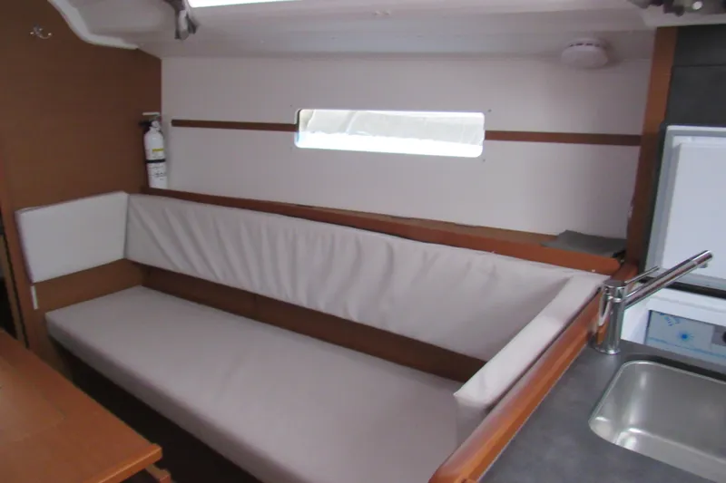Slide: The Image of Interior of 2023 Jeanneau Sun Odyssey 349 sailboat, featuring a cozy seating area and kitchenette. - 8