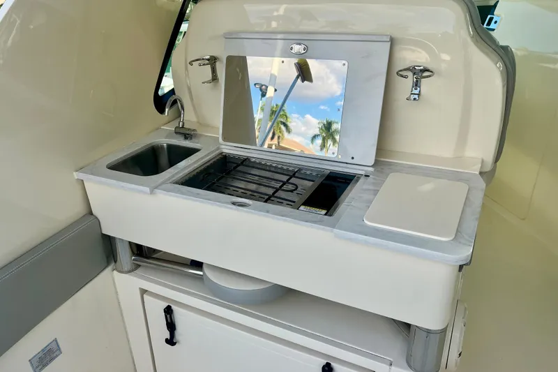 Slide: The Image of 2023 Scout 350 LXZ boat kitchenette with sink, stove, and cutting board. - 10