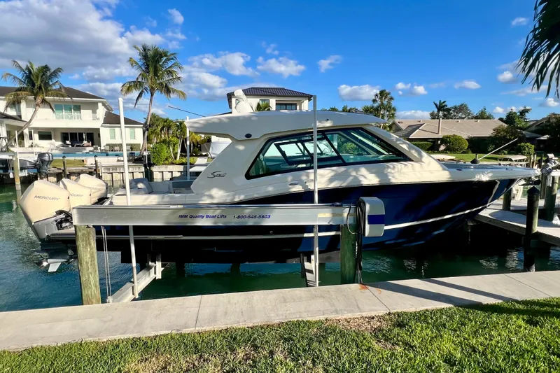 Slide: The Image of 2023 Scout 350 LXZ boat docked in a scenic waterfront setting. - 13
