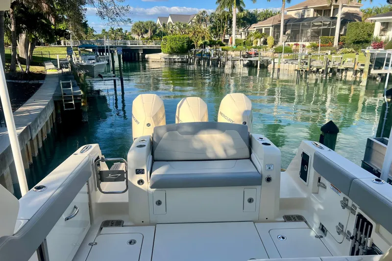 Slide: The Image of 2023 Scout 350 LXZ boat docked in a scenic waterfront setting. - 5