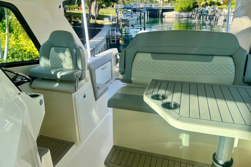 Slide: The Image of 2023 Scout 350 LXZ boat interior with luxurious seating and table, dockside view. - 7