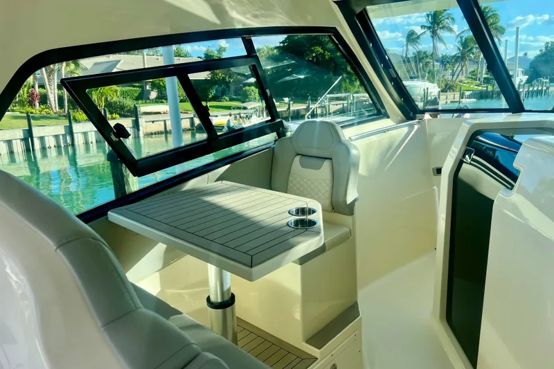 Slide: The Image of 2023 Scout 350 LXZ boat interior with seating and table, overlooking a scenic waterfront. - 8