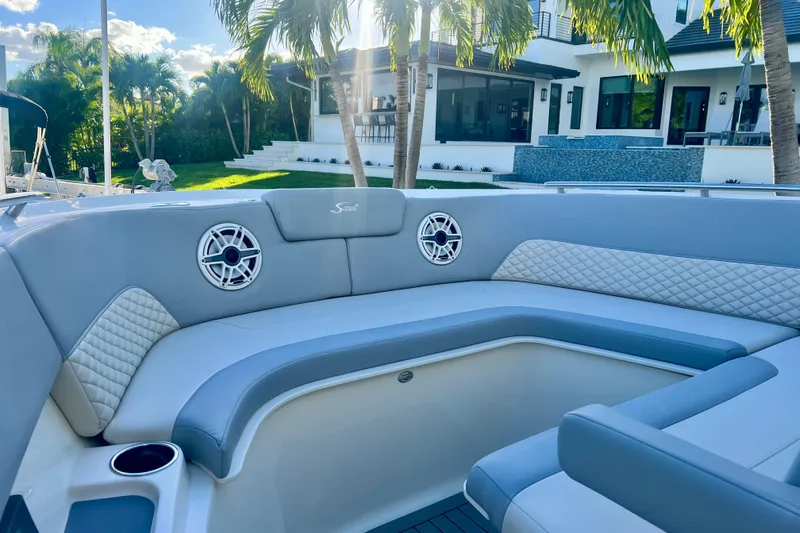 Slide: The Image of 2023 Scout 350 LXZ boat interior with luxurious seating and speakers, near a modern house. - 9
