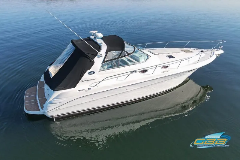Slide: The Image of 1997 Sea Ray 330 Sundancer boat on calm water, featuring sleek design and black canopy. - 14