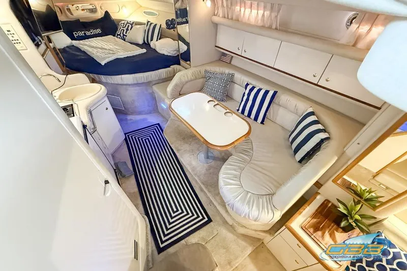 Slide: The Image of 1997 Sea Ray 330 Sundancer interior with cozy seating, striped pillows, and a small dining table. - 21