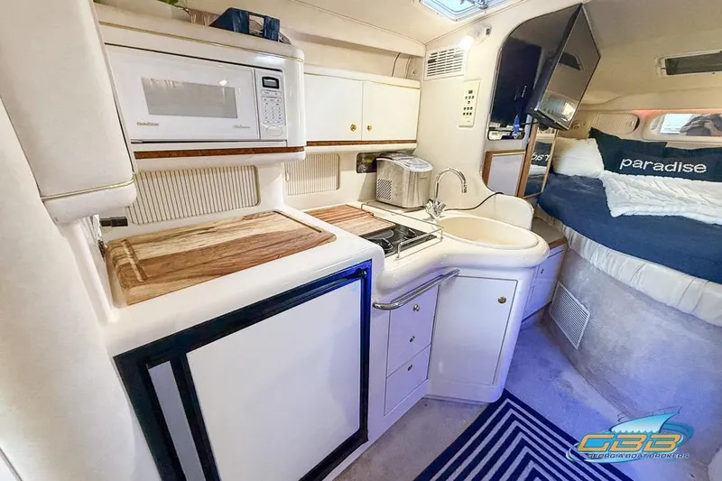 Slide: The Image of 1997 Sea Ray 330 Sundancer interior with kitchenette and cozy sleeping area. - 24