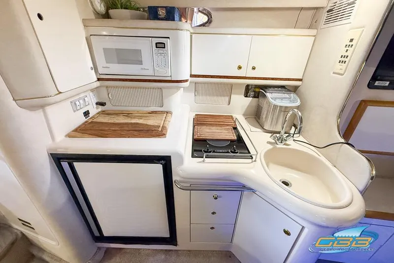 Slide: The Image of 1997 Sea Ray 330 Sundancer yacht kitchen with microwave, stove, sink, and storage cabinets. - 29