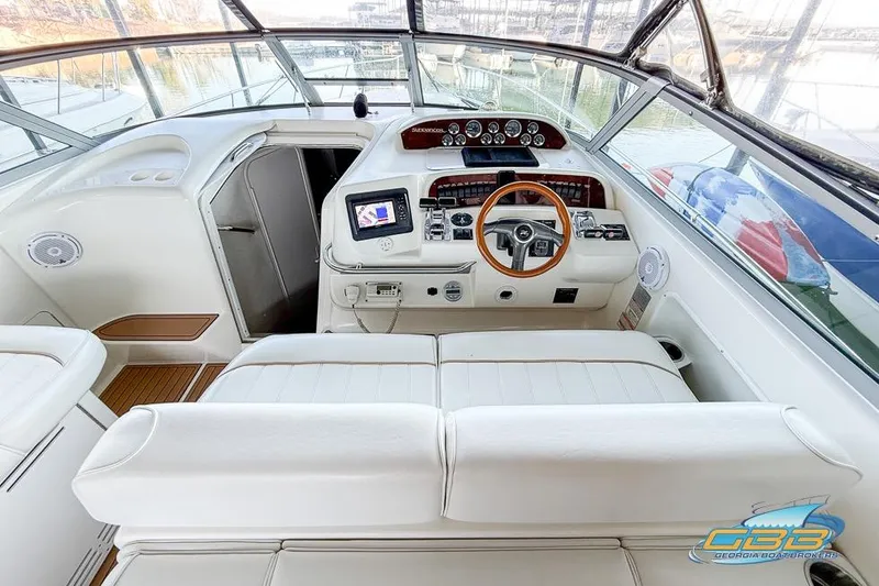 Slide: The Image of 1997 Sea Ray 330 Sundancer helm with white seating and wooden steering wheel. - 38