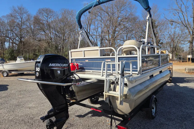 Slide: The Image of 2021 Sun Tracker Bass Buggy 16 XL pontoon boat with Mercury engine, parked outdoors. - 5