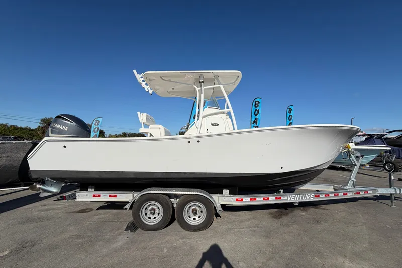 Slide: The Image of 2013 Regulator 24 Forward Seating boat on trailer, side view under clear blue sky. - 1