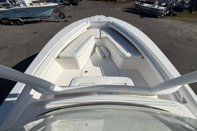 Slide: The Image of 2013 Regulator 24 Forward Seating boat with T-top and rod holders, docked under clear skies. - 19