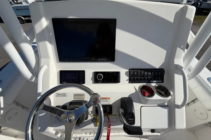 Slide: The Image of Compass on 2013 Regulator 24 Forward Seating boat, docked with other vessels in background. - 32