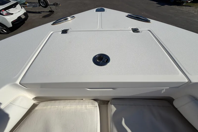 Slide: The Image of 2013 Regulator 24 Forward Seating boat anchor compartment, open lid, outdoor setting. - 64