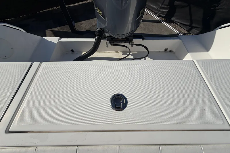 Slide: The Image of 2013 Regulator 24 Forward Seating boat with open storage compartment and visible engine. - 86