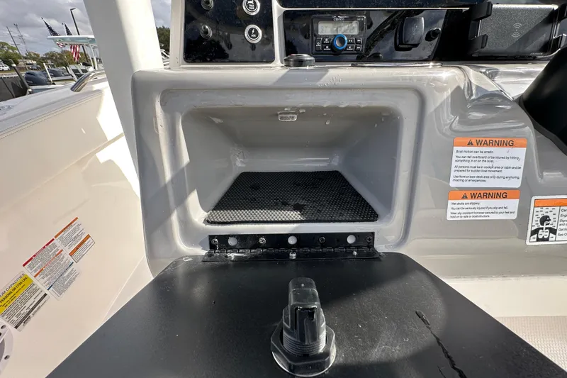 Slide: The Image of 2024 Robalo R232 Explorer boat dashboard with storage compartment and warning labels. - 18