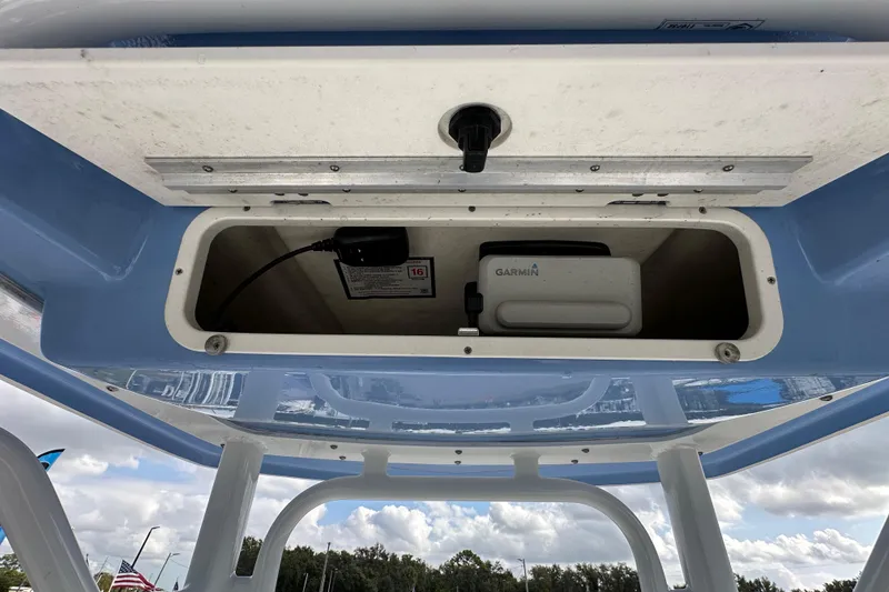 Slide: The Image of 2024 Robalo R232 Explorer boat storage compartment with Garmin device, under blue canopy. - 27