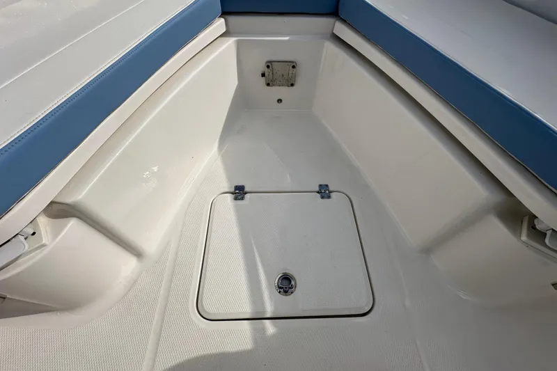Slide: The Image of 2024 Robalo R232 Explorer boat interior with blue and white seating and storage hatch. - 31
