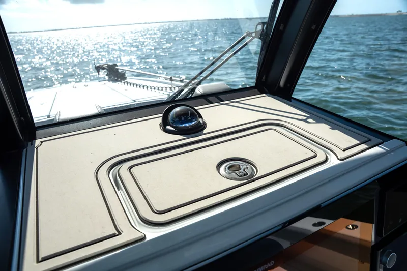 Slide: The Image of 2024 Freeman 28 boat dashboard with compass, overlooking sparkling ocean waters. - 24