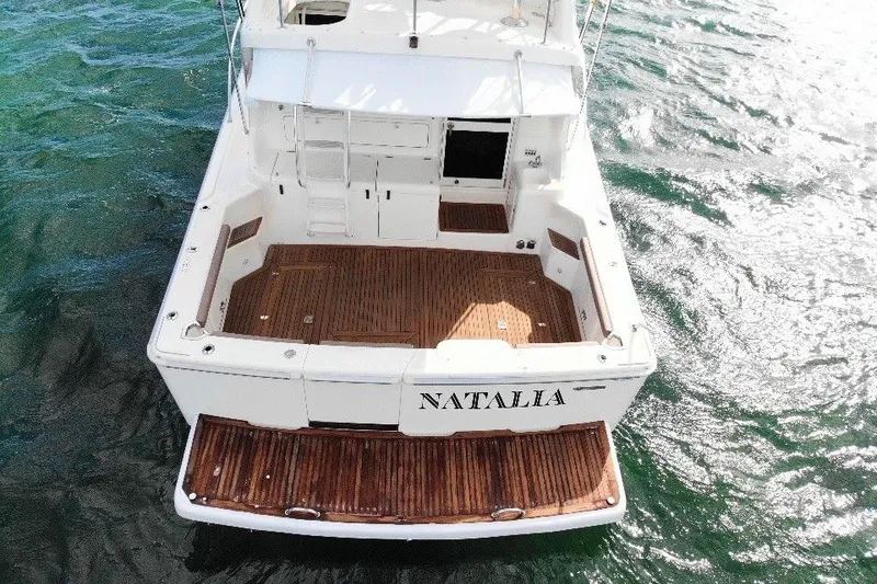 Slide: The Image of 1999 Wellcraft 400 Coastal boat with wooden deck, named "Natalia," on water. - 12