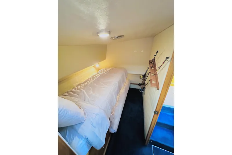 Slide: The Image of 1999 Wellcraft 400 Coastal cabin interior with bed and fishing rod storage. - 31
