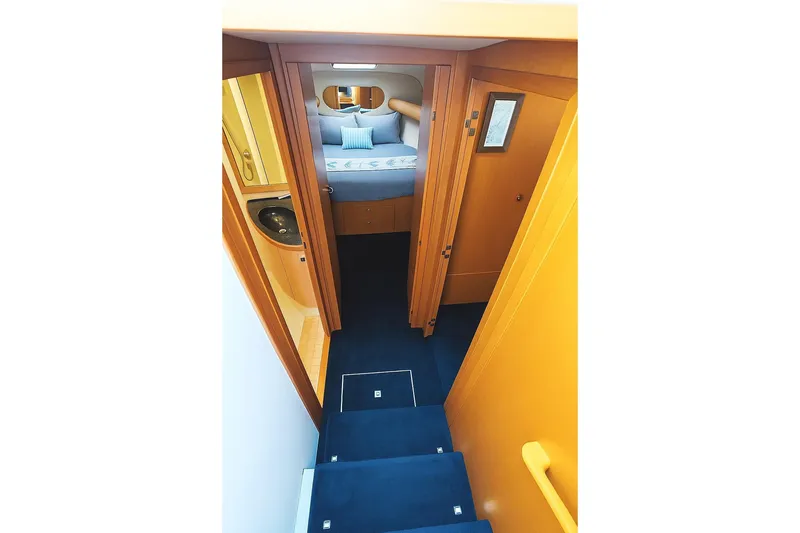 Slide: The Image of 1999 Wellcraft 400 Coastal yacht interior with blue carpeted stairs and cozy bedroom. - 5