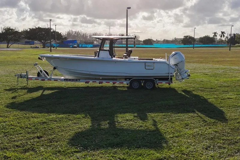 Slide: The Image of 2023 Seahunt 30 GameFish Coffin Box boat on trailer in grassy field. - 5