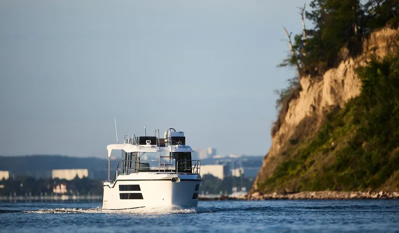 Slide: The Image of Northman 1050 boat cruising near a rocky coastline, 2025 model. - 12