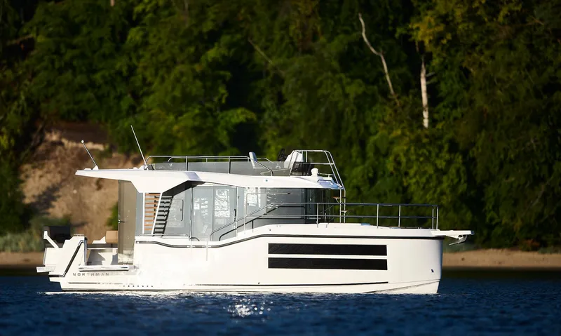 Slide: The Image of Modern 2025 Northman 1050 yacht cruising on a serene lake with lush green forest backdrop. - 13